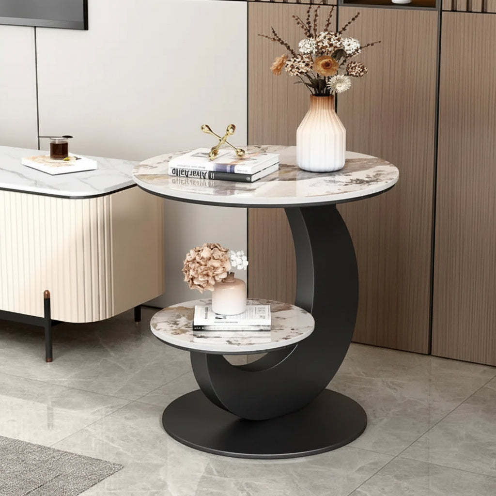 Modern side table with marble top and black curved base in a room setting.


